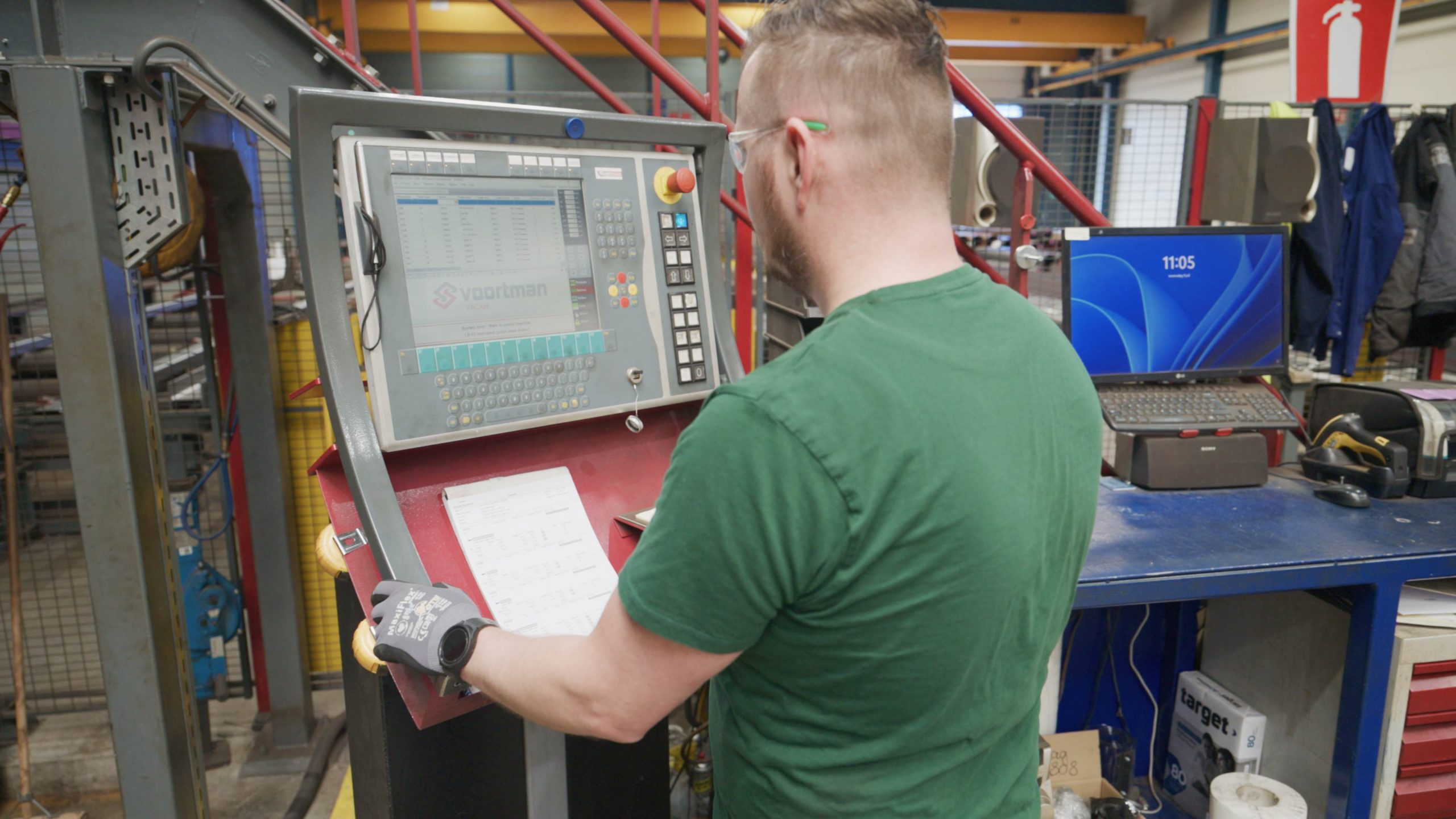 Man bedient een CNC-machine via een digitaal bedieningspaneel in een werkplaats.