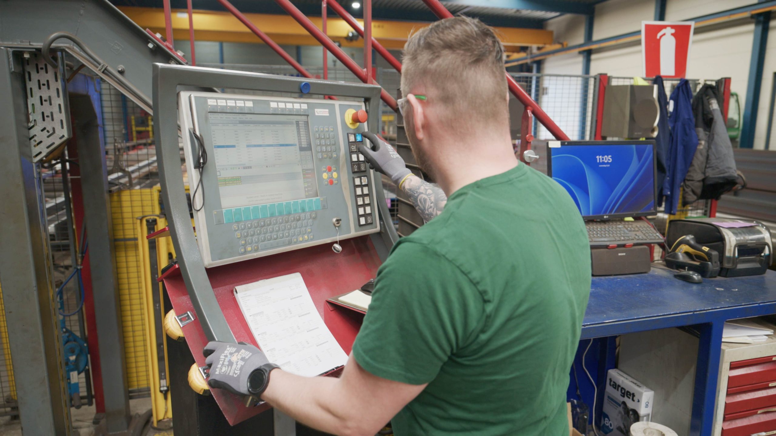 Man bedient een CNC-machine via een digitaal bedieningspaneel in een werkplaats.