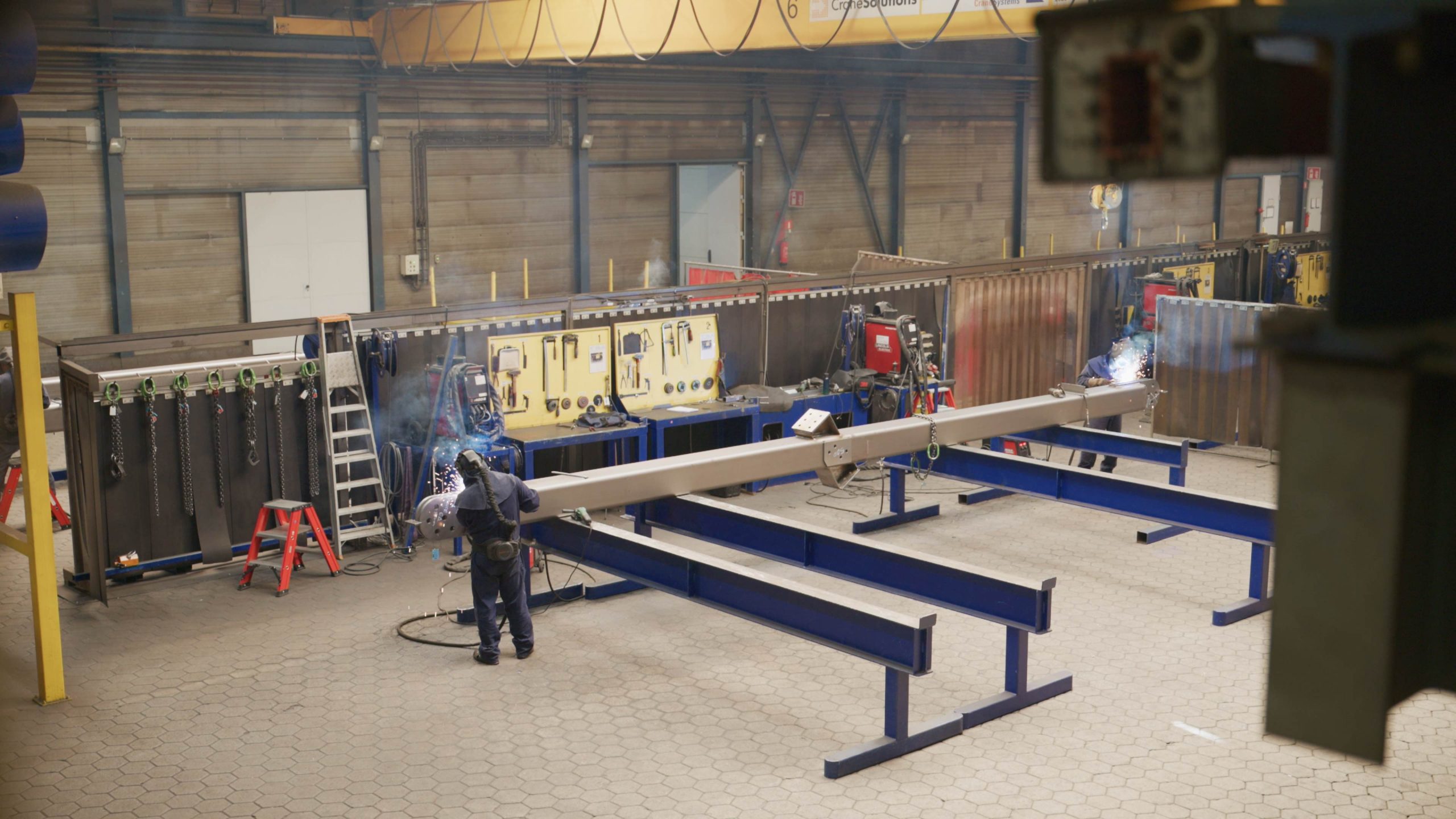 Lasser werkt aan metalen constructie in werkplaats.